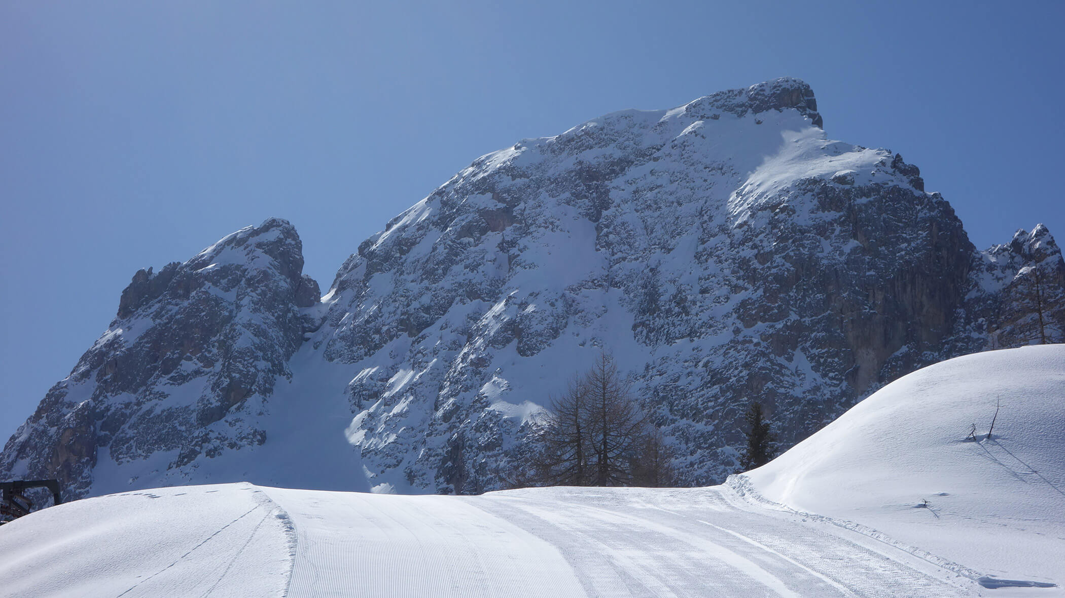 Schneebedeckter Berg mit blauem Himmel und Bäumen an einem sonnigen Wintertag. - Garni Tschurtschenthaler