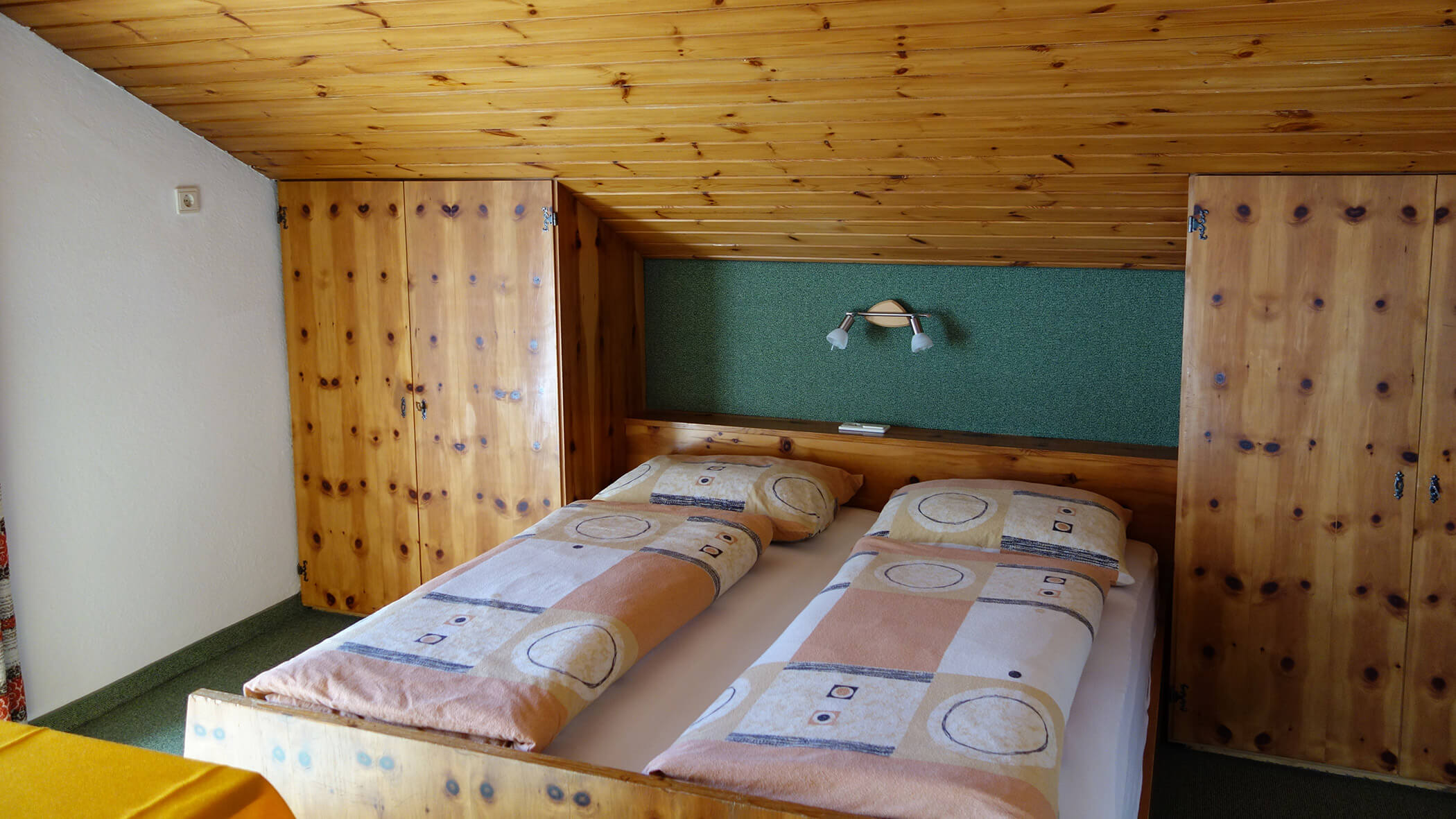 Gemütliches Schlafzimmer mit zwei zusammengeschobenen Einzelbetten, holzgetäfelten Wänden und Decken und geometrischem Bettzeug. - Garni Tschurtschenthaler